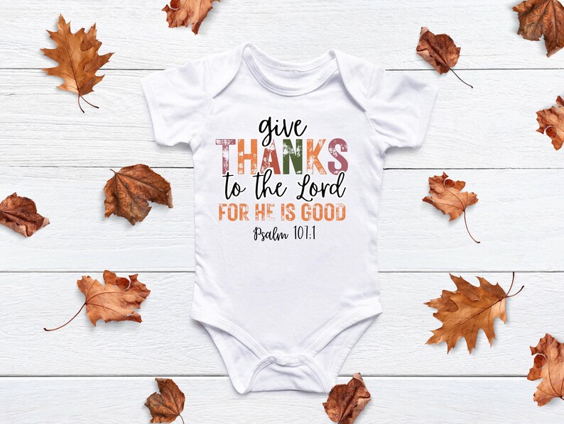 May include: White baby onesie with the text "give thanks to the Lord for he is good Psalm 101:1" in colorful, distressed lettering.