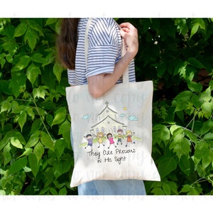 May include: A white canvas tote bag with a colorful illustration of children walking towards a church building. The text "They Are Precious In His Sight" is printed below the illustration.
