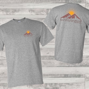 May include: Grey t-shirt with a mountain and sun graphic on the front and the text "Act Like Men" and a mountain and sun graphic with the text "Be watchful, stand firm in the faith, act like men, be strong." on the back.