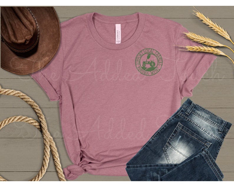 Pu&ograve; includere: Una maglietta color malva con una grafica verde di un trattore e il testo "Support Local Farmers Virginia, West Virginia".