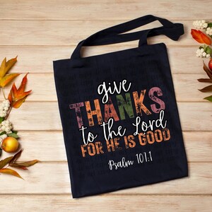 May include: A navy blue tote bag with the text "give THANKS to the Lord FOR HE IS GOOD" in colorful letters. The text "Psalm 101:1" is printed in white below the main text.