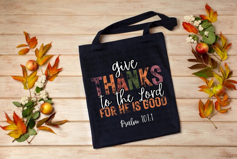 May include: A navy blue tote bag with the text "give THANKS to the Lord FOR HE IS GOOD" in colorful letters. The text "Psalm 101:1" is printed in white below the main text.