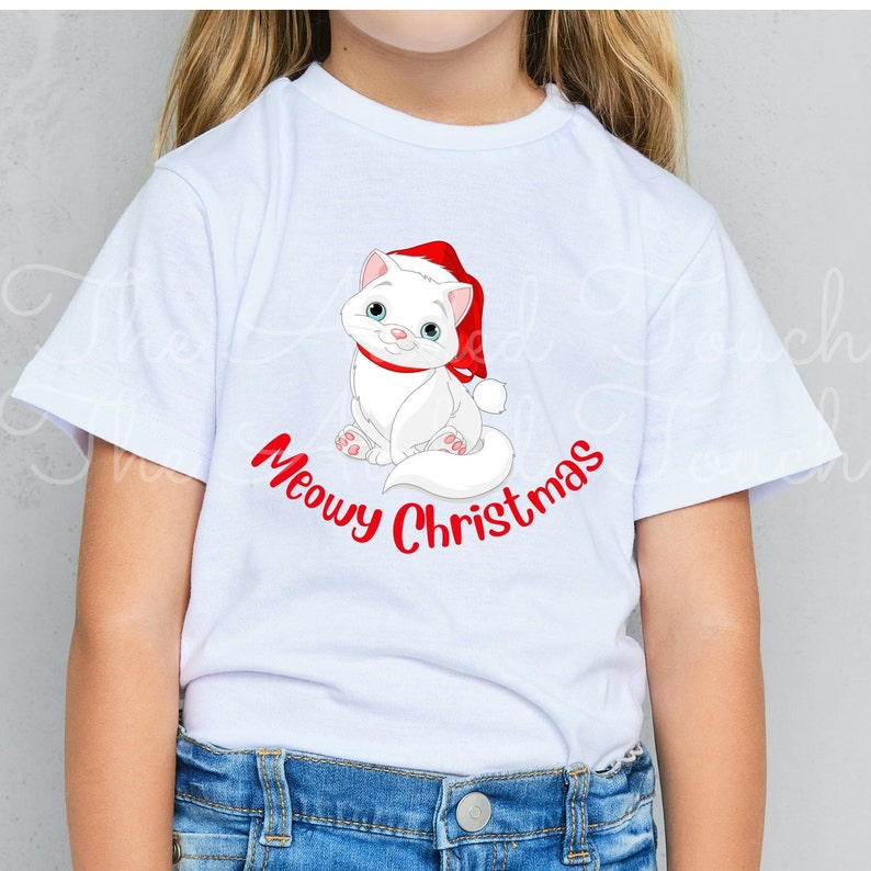 May include: White t-shirt featuring a cartoon cat wearing a Santa hat and a red collar. The cat is sitting and smiling, with the words "Meowy Christmas" in red script below. A festive holiday tee.