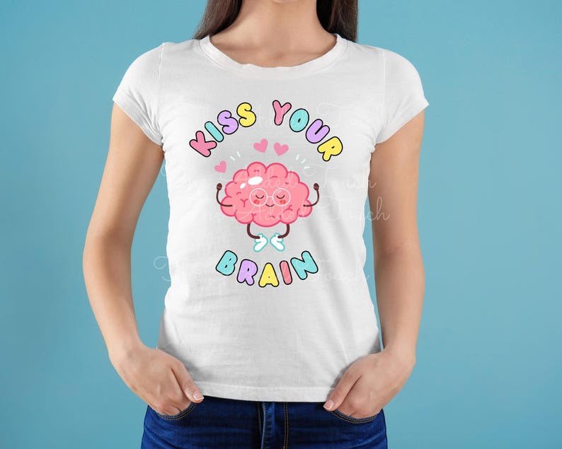 May include: White t-shirt with a pink cartoon brain wearing glasses and holding its hands up. The text "Kiss Your Brain" is written in rainbow colors above the brain.