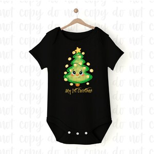 May include: Black baby onesie with a cartoon Christmas tree design. The green tree has a smiling face, yellow lights, and a star on top. The text "My 1st Christmas" is printed below the tree in gold.