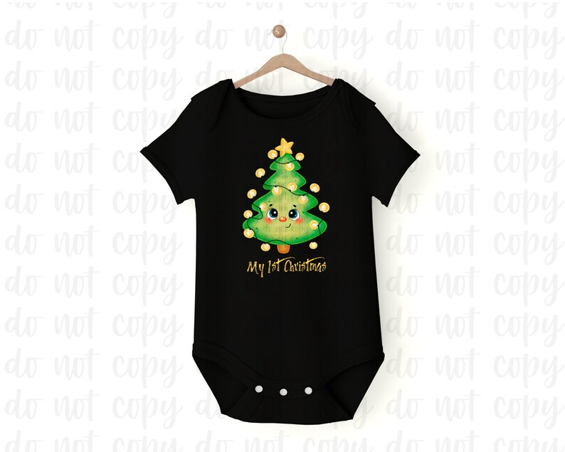 May include: Black baby onesie with a cartoon Christmas tree design. The green tree has a smiling face, yellow lights, and a star on top. The text "My 1st Christmas" is printed below the tree in gold.
