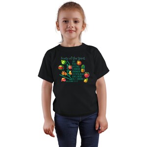 May include: A black t-shirt with a graphic of fruit and the text "Fruits of the Spirit" with a list of qualities, "Joy, Peace, Patience, Kindness, Goodness, Faithfulness, Gentleness, Self-Control", and the scripture reference "Galatians 5:22-23".