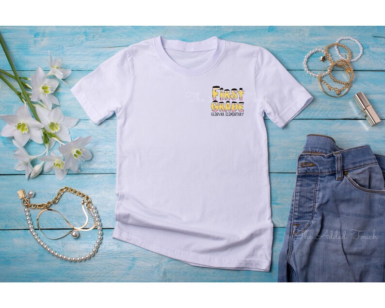 May include: White t-shirt with the text "First Grade" in yellow and black letters, with the words "Glowfire Elementary" underneath.