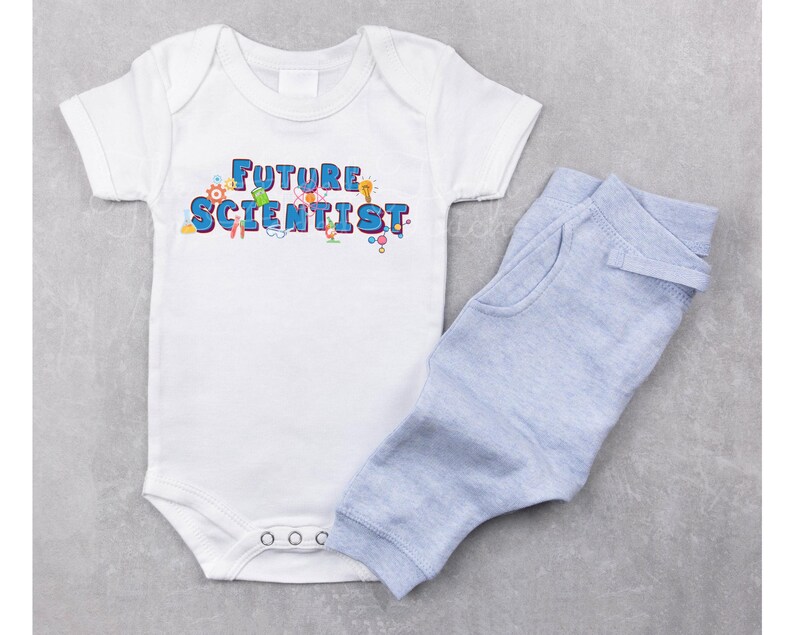 Pu&ograve; includere: Un body bianco per neonato con il testo "FUTURE SCIENTIST" in lettere blu e grafiche colorate a tema scientifico. Il body &egrave; abbinato a pantaloni blu chiaro per neonato.