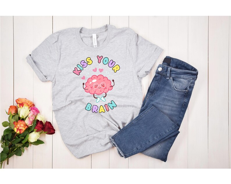 May include: A gray t-shirt with a pink brain cartoon wearing glasses and the text "Kiss Your Brain" in rainbow colors.