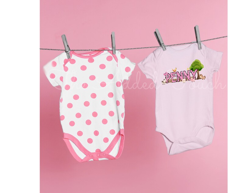 May include: Two pink baby onesies hanging on a clothesline. One onesie has white polka dots and the other has the name "PENNY" with farm animals and a tree.