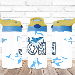 May include: A blue and yellow water bottle with a shark design and the name "John" printed on it.