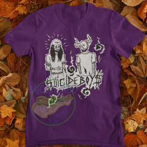 May include: Purple t-shirt with a black and white graphic of two men with the text "Suicideboy$  " printed on the front.
