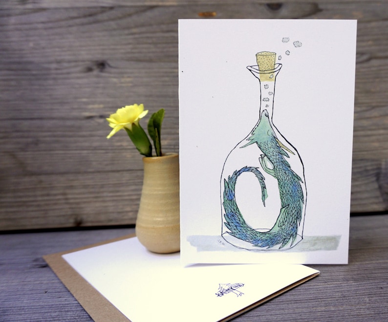 May include: A green and blue dragon is trapped inside a clear glass bottle with a cork stopper. The dragon is curled up in the bottle, with its head and tail visible. The bottle is sitting on a white background.