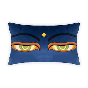 Puede incluir: Una almohada de terciopelo azul con ojos bordados y un punto amarillo en el centro. Los ojos son verdes con detalles naranja y blanco.