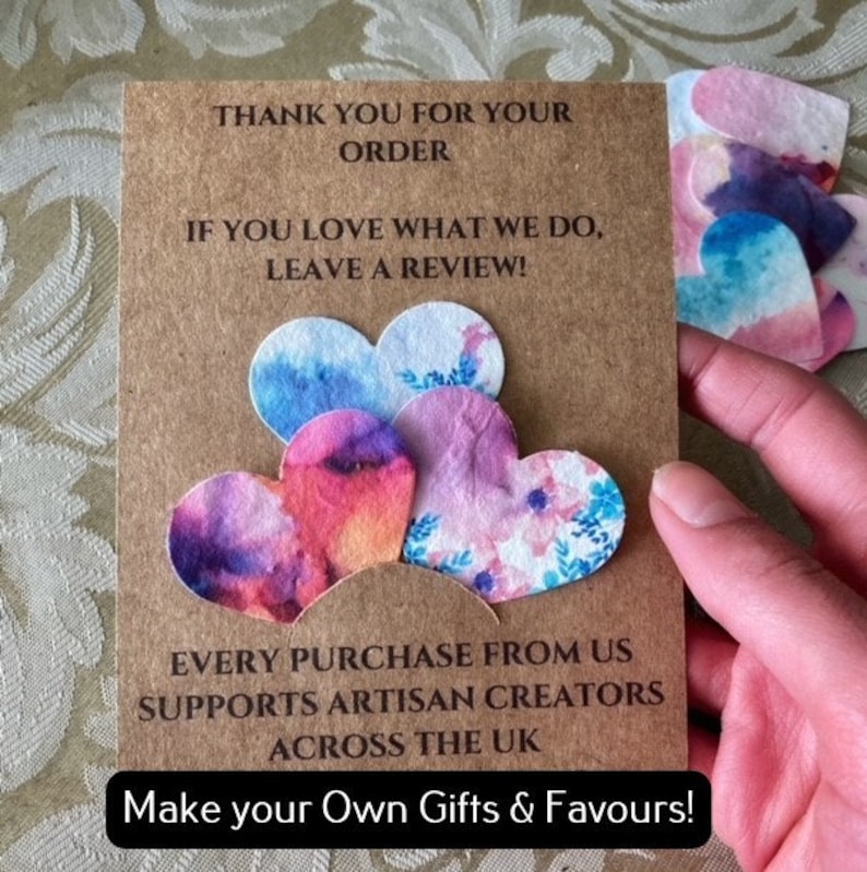 May include: A brown card with the text "Thank you for your order. If you love what we do, leave a review!" and "Every purchase from us supports artisan creators across the UK. Make your own gifts & favours!"  The card has five colourful paper hearts attached to it.