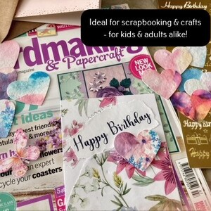 May include: A close-up of a craft project featuring a card that reads "Happy Birthday" and a selection of colourful paper hearts. The hearts are perfect for scrapbooking and crafting.