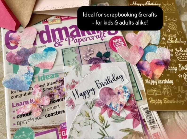 May include: A close-up of a craft project featuring a card that reads "Happy Birthday" and a selection of colourful paper hearts. The hearts are perfect for scrapbooking and crafting.