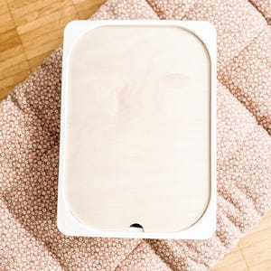 Op de afbeelding: Witte houten opbergdoos met een deksel. De doos staat op een roze en wit bloemmotief.