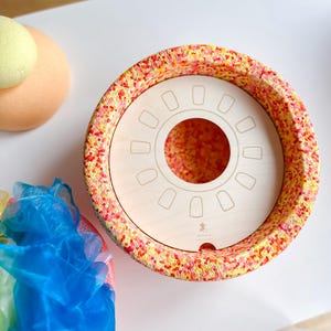 Può includere: Un vaso in ceramica rosso e giallo macchiettato con un inserto in legno che presenta un taglio circolare e otto tagli rettangolari più piccoli. Il vaso ha una smaltatura rosso e giallo macchiettata.