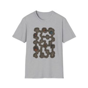 May include: A light gray t-shirt featuring a detailed, colorful map of a dungeon. The map includes various rooms, passages, and symbols, such as a skull, flags, and flames. The shirt is made of a soft material.