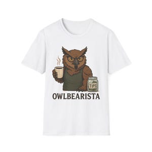 May include: White t-shirt with a cartoon owl barista holding a cup of coffee and a jar labeled "TIPS". The text "OWLBEARISTA" is printed below the owl.