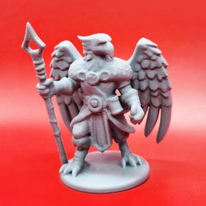 May include: A gray 3D printed miniature of a humanoid figure with bird wings and a staff. The figure is wearing a tunic and has a bird-like head.