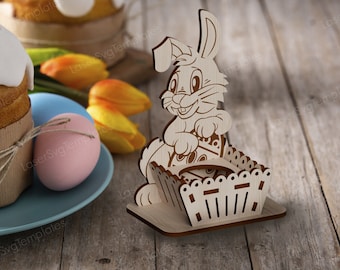 May include: A wooden Easter bunny figurine with a basket, set on a wooden surface. The bunny is smiling and holding the basket. Easter eggs, tulips, and a cake are in the background.