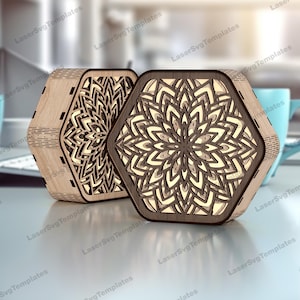 Può includere: Due scatole decorative esagonali in legno con intricati motivi floreali. Una scatola è di colore chiaro, l'altra è marrone scuro. Le scatole sono a strati, creando un effetto 3D. Sono illuminate dall'interno, creando un bagliore caldo.