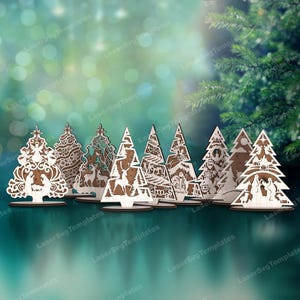 May include: Set of eight wooden Christmas tree ornaments with intricate cutouts and various designs, including a nativity scene, a reindeer, and a snowman. The ornaments are arranged on a table against a blurred background of green foliage.