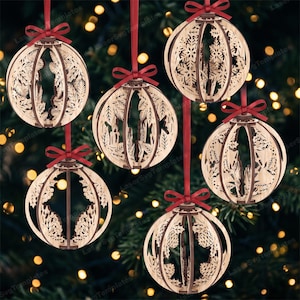 Op de afbeelding: Vijf bolvormige houten ornamenten met ingewikkelde lasergesneden ontwerpen van dennenappels, hulstbladeren en kaarsen. Elk ornament is gemaakt van gelaagd lichtgekleurd hout en hangt aan een dun rood lint dat bovenaan in een strik is geknoopt.