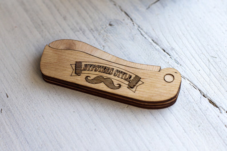 Op de afbeelding: Een houten kam met een snor en de tekst "Hipsters Style" erop gegraveerd.