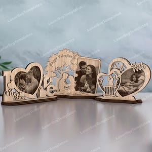 Puede incluir: Tres marcos de fotos de madera con diseños cortados con láser. Un marco deletrea "I Love You" con una foto en forma de corazón. Otro presenta un árbol con "Happy Valentine" y una pareja. El tercero tiene forma de corazón.
