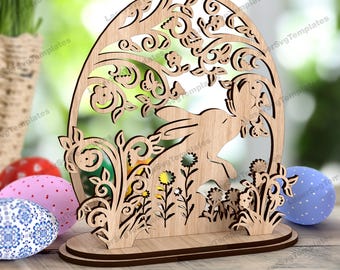 Könnte beinhalten: Holzschnitt in Form eines Ostereis mit einem Hasen und einem Blumendesign. Der Schnitt ist auf einem Holzsockel.