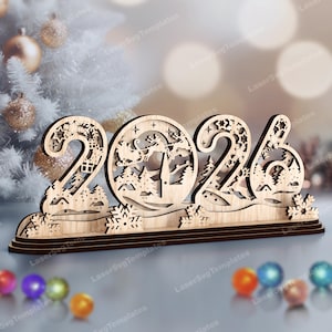 Può includere: Decorazione natalizia in legno con l'anno 2026, intagliata con fiocchi di neve e una scena di Babbo Natale. Il design è su una base a più livelli, perfetto per l'arredamento festivo.