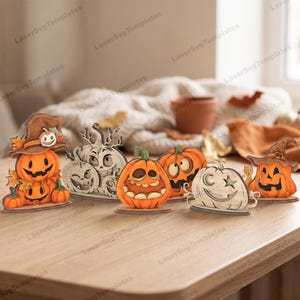 May include: A collection of six decorative wooden Halloween ornaments featuring carved pumpkins with various expressions, some wearing witch hats, rendered in orange, brown, and natural wood tones, arranged on a flat surface.