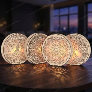 Pode incluir: Quatro painéis circulares de madeira iluminados com designs intrincados cortados a laser. Dois painéis exibem um motivo de árvore com raízes e ramos, enquanto os outros dois apresentam padrões geométricos detalhados de mandalas.