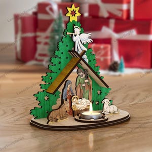 May include: A wooden Christmas nativity scene with a green tree-shaped backdrop, featuring figures of Mary, Joseph, and baby Jesus. Includes a star, angel, donkey, and lamb. A lit candle sits in front of the scene, creating a warm glow.