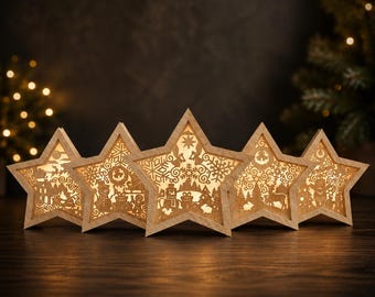 May include: A set of five light-colored wooden star-shaped ornaments, each featuring intricate laser-cut silhouettes of winter scenes including snowmen, reindeer, pine trees, and snowflakes, illuminated from within by a warm glowing light.
