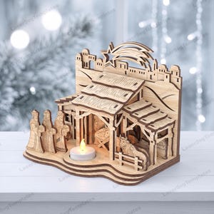 May include: A laser-cut wooden nativity scene featuring a stable structure, a star, and figures of three wise people, a cow, and a sheep. The display includes a circular cutout for a small white tea light candle that emits a warm yellow glow.