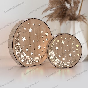 Può includere: Due progetti di luce notturna in legno a forma di luna e stelle. Il design più grande presenta una luna crescente con nuvole e stelle. Il design più piccolo è simile ma più piccolo. Entrambi i progetti sono in legno e hanno una finitura marrone chiaro.