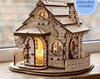 May include: A wooden miniature house with a stone-like facade, arched windows, and a chimney. The house features a decorative fence, a front door, and a lit candle inside. The text "Instruction included" is in a blue circle.