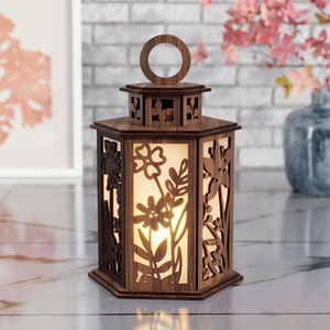 May include: A wooden lantern with a hexagonal shape and intricate floral cutouts. The lantern has a frosted glass panel and a warm glow emanating from inside.