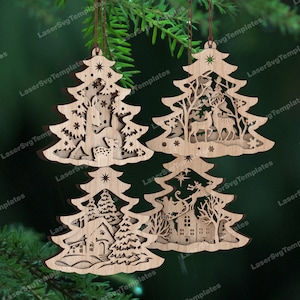 Op de afbeelding: Vier houten kerstboomversieringen met ingewikkelde lasergesneden ontwerpen. De ornamenten tonen een hert en een fawn, een winterscène met een huis, een kerstman in een slee en een winterscène met een huis en bomen.