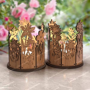 Op de afbeelding: Twee houten kaarshouders met een bloemmotief. De houders zijn gemaakt van lasergesneden hout en bevatten een verscheidenheid aan bloemen, waaronder madeliefjes, rozen en lelies. De houders zijn perfect om elke woning een vleugje elegantie te geven.