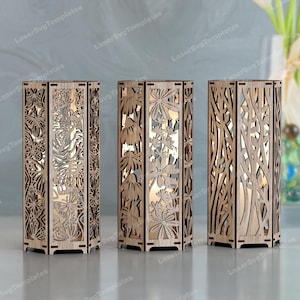 Può includere: Tre portacandele in legno con intricati disegni tagliati al laser. I disegni includono farfalle, fiori e rami. I portacandele rettangolari emettono un bagliore caldo e invitante.