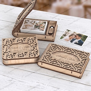 Op de afbeelding: Houten trouwherinneringsdozen met ingewikkelde bloemmotieven. Eén doos is open en toont foto's en een USB-stick. Twee andere dozen zijn gesloten, elk met een gepersonaliseerde naam en datum. Er is ook een foto van een stel aanwezig.