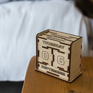 Puede incluir: Un calendario de madera que muestra la fecha del 6 de septiembre, con el día de la semana indicado como jueves.