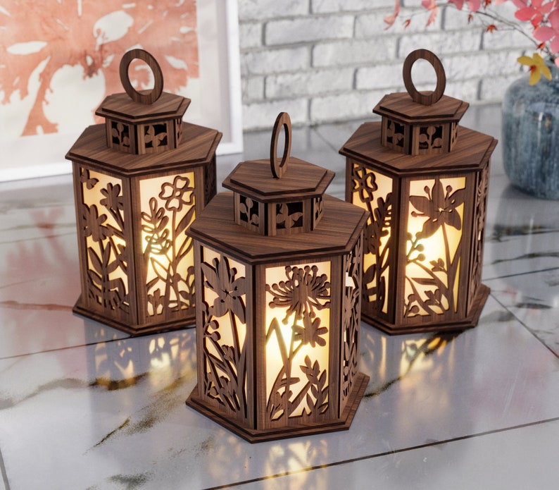 May include: Three wooden lanterns with intricate floral designs and a warm glow emanating from within. The lanterns are hexagonal in shape and have a decorative handle at the top.