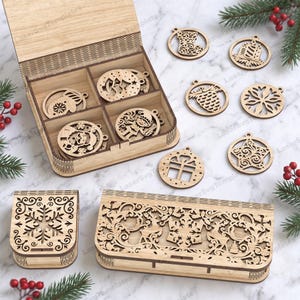May include: A set of laser-cut wooden Christmas ornaments featuring various holiday designs like a stocking, pinecone, snowflake, and star, stored in a partitioned wooden box. Two additional decorative wooden boxes with intricate cutouts are included.